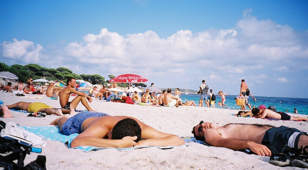 De nombreuses personnes allongées sur des serviettes de plage, en bord de mer et au soleil