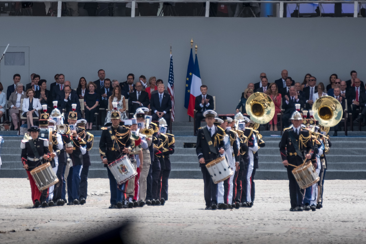 Photo de la fanfare militaire du défilé du 14 juillet, avec la tribune officielle en arrière plan, où se trouvent notamment Emmanuel Macron et Donald Trump