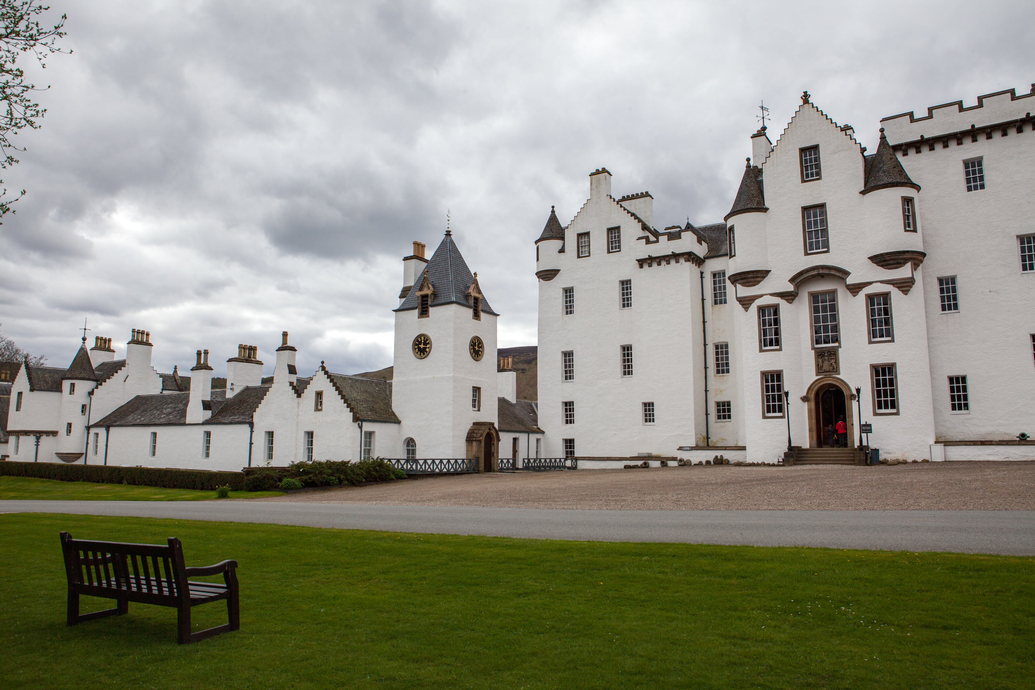 Photo of the front of a white Scottish castle, with a bench on a grassy area in front.