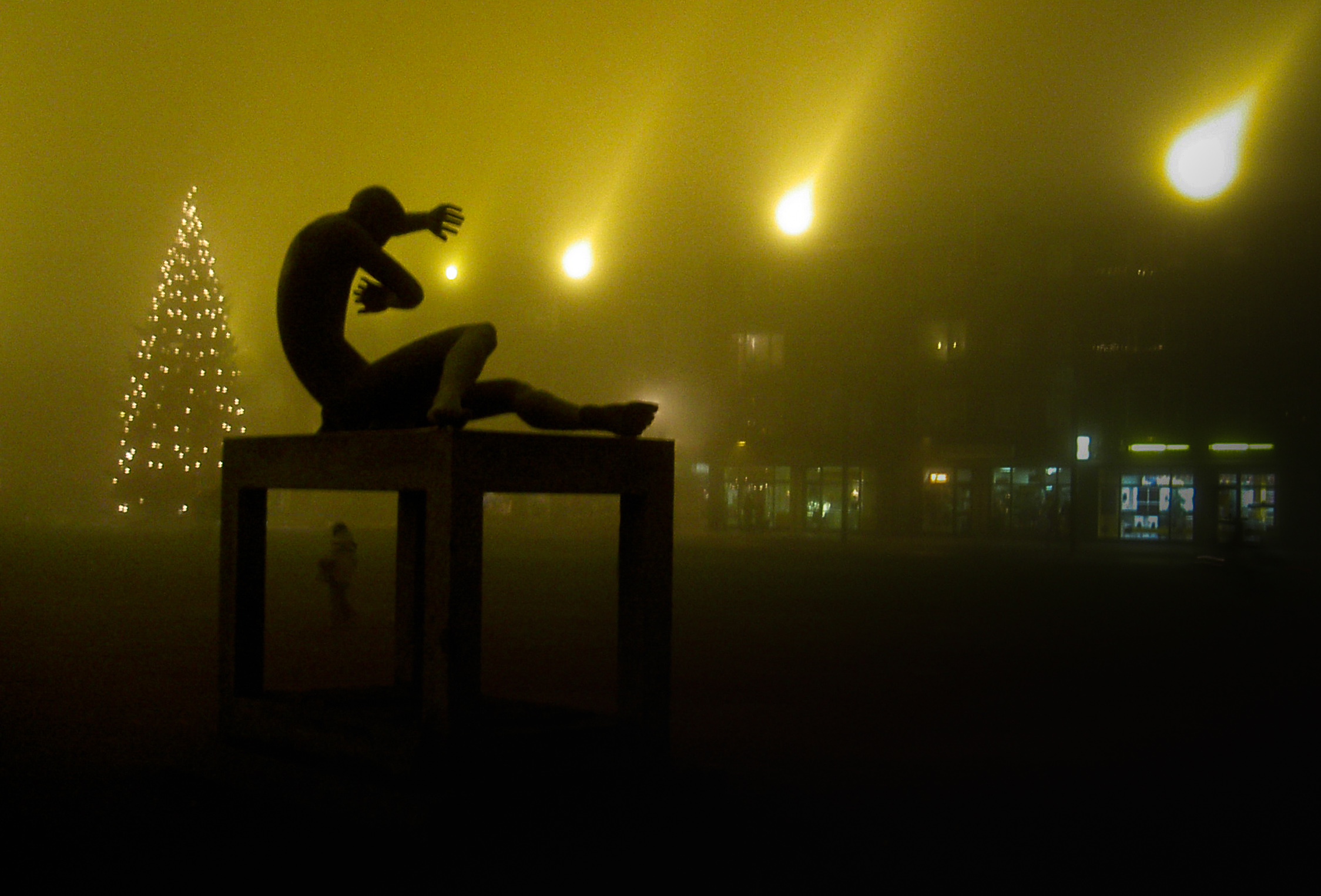 Night photo of a statue silhouette giving the impression to protect itself with its arms of luminous spots