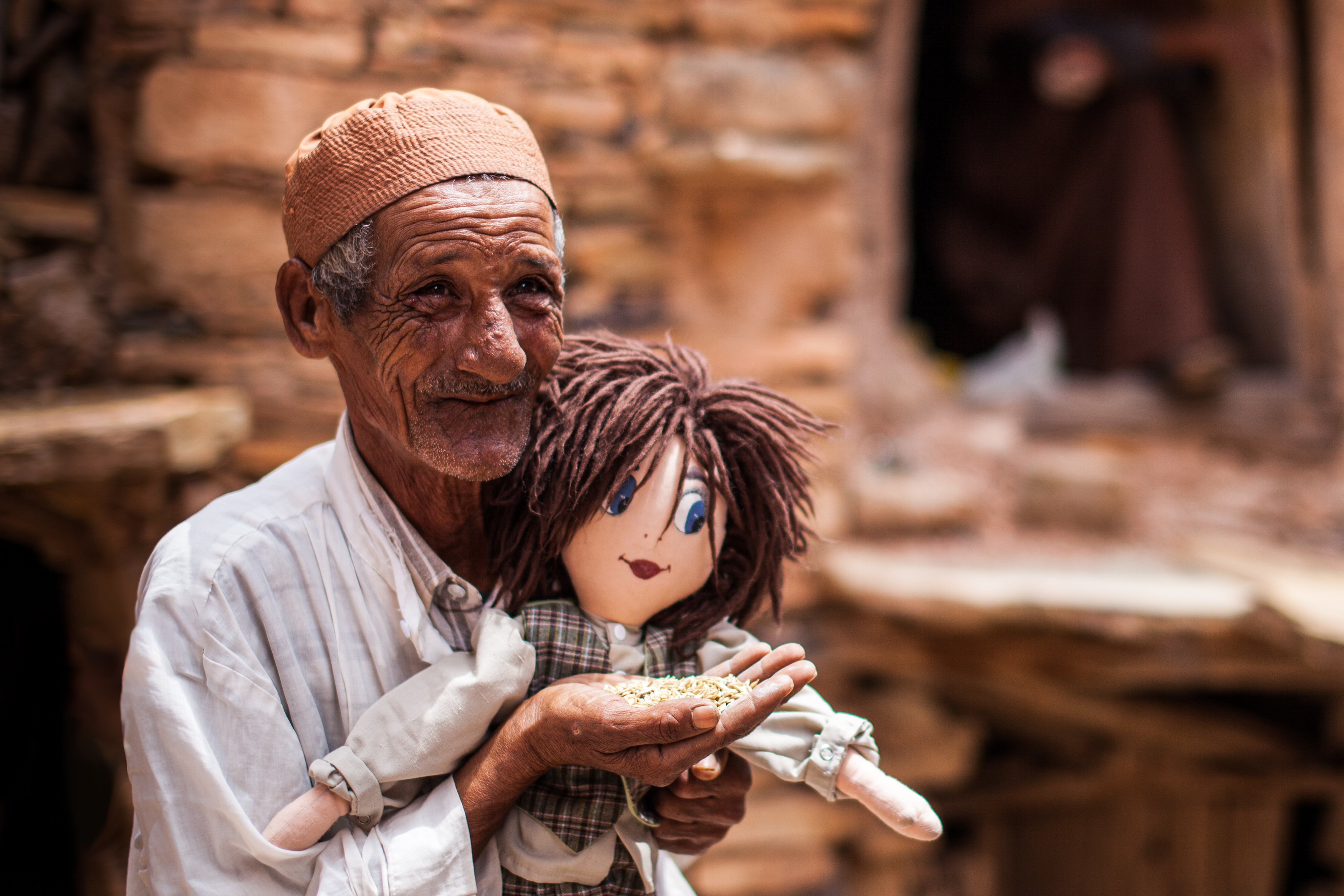 Photo of an old Moroccan man Lamine of an Igoudar (i.e. guardian of a community granary), with a rag doll.
