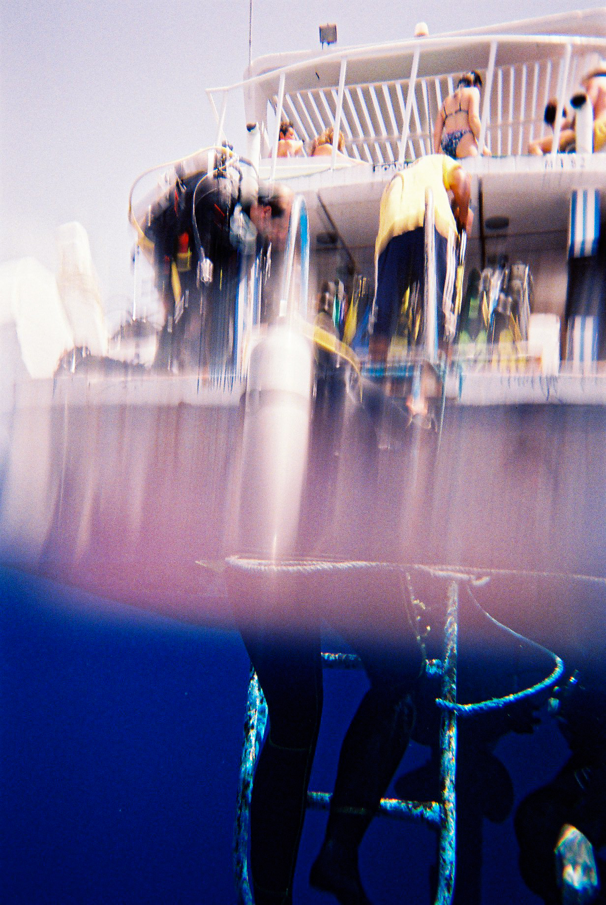 Photo taken at the limit between air and water, in the sea, with a boat, and a diver on a ladder
