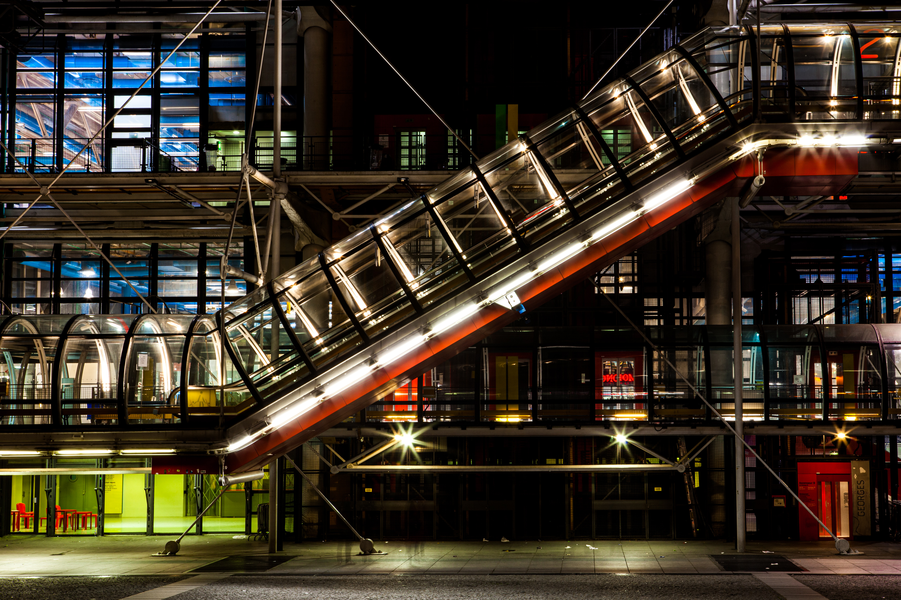 Photo of the exterior escalator of the Pompidou Center, at night, with lights of different colors in the building