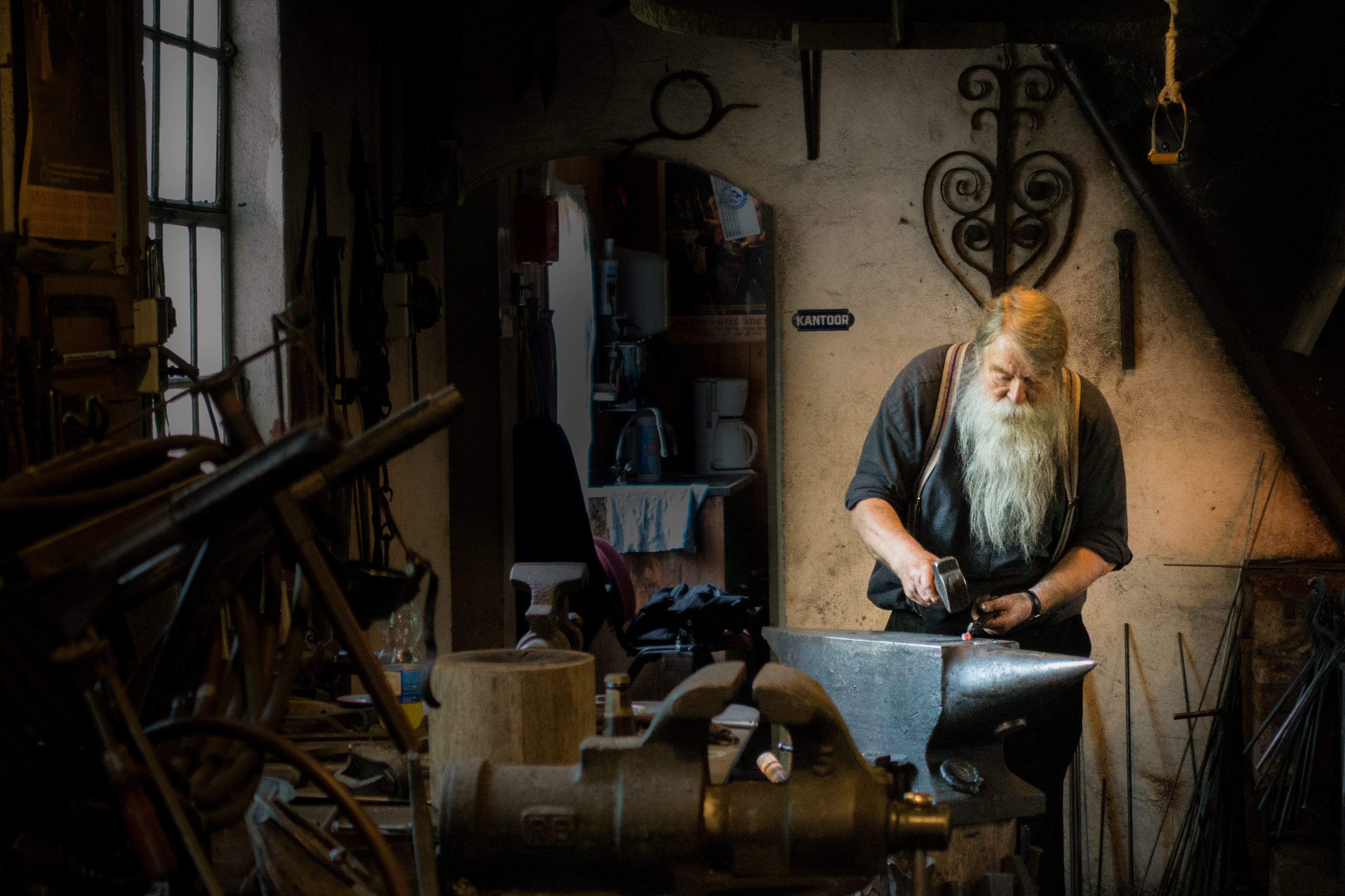 Photo of a blacksmith working with a hammer and anvil